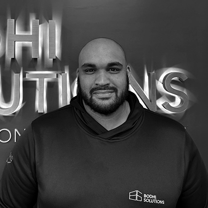 Man with beard wearing a Bodhi Solutions hoodie standing in front of a company logo wall.