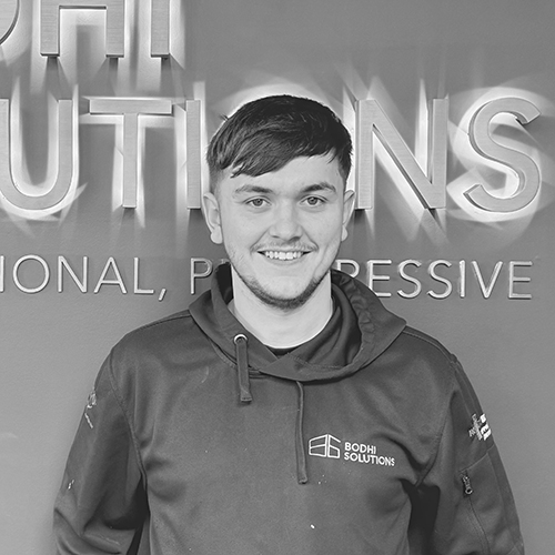 Smiling man with short hair wearing Bodhi Solutions hoodie standing in front of a company sign.