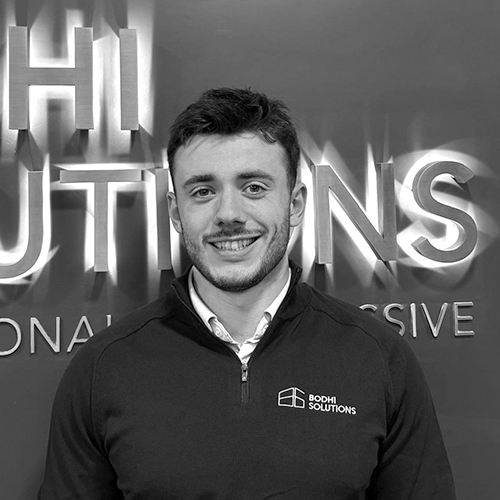 Smiling man in a Bodhi Solutions jacket standing before a wall with the company name.