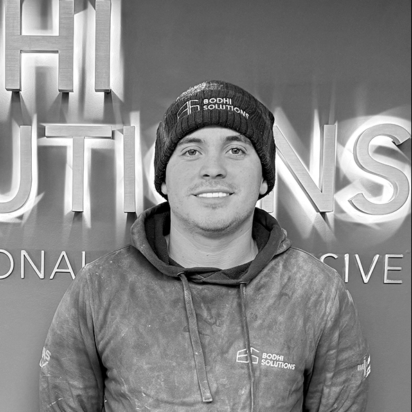Man wearing Bodhi Solutions beanie and hoodie standing against a wall with lettering.