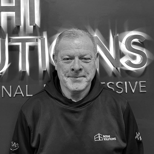 Man in a Bodhi Solutions hoodie standing in front of a wall with partially visible text.
