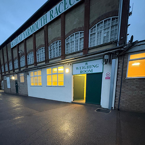 Entrance to the brightly lit Weighing Room at Great Yarmouth Racecourse at dusk.