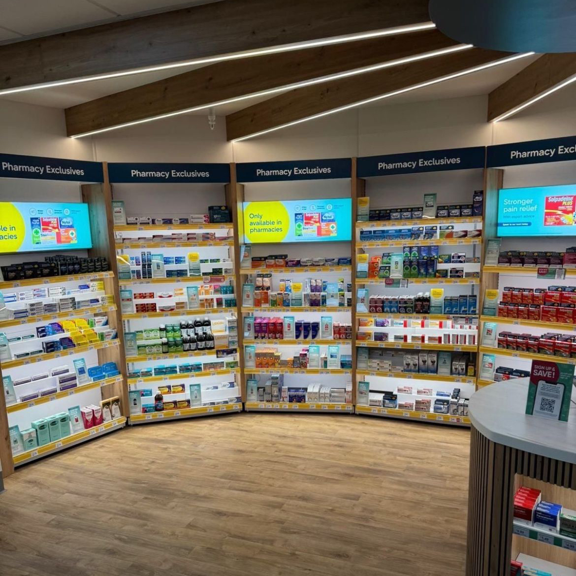 Pharmacy shelves labeled Pharmacy Exclusives stocked with various medicines and health products.